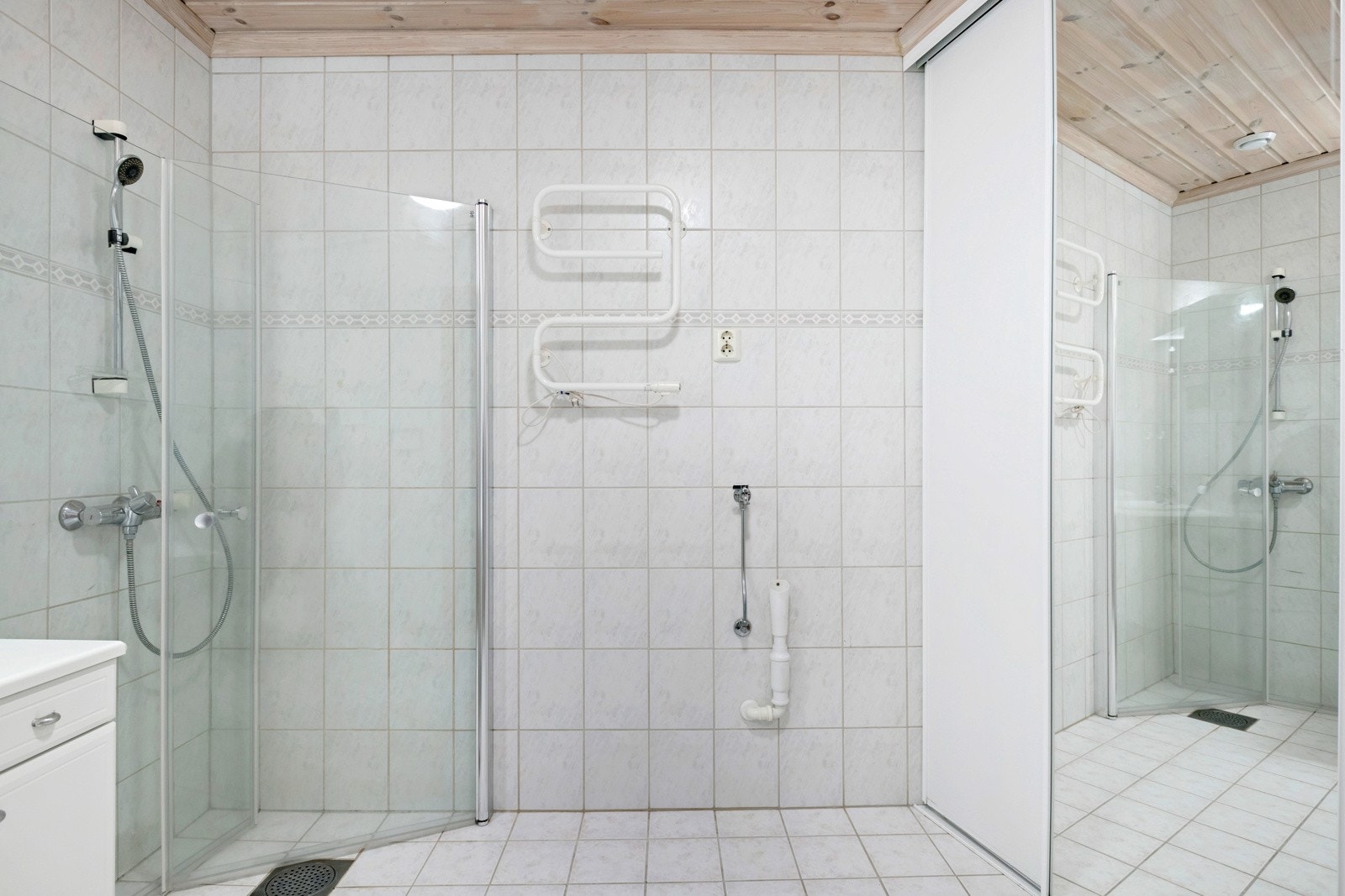 Badet er utstyrt med dusj med innfellbare glassvegger, servantseksjon med skap, nedfelt porselenvask og speil med lys over. Galleribilde