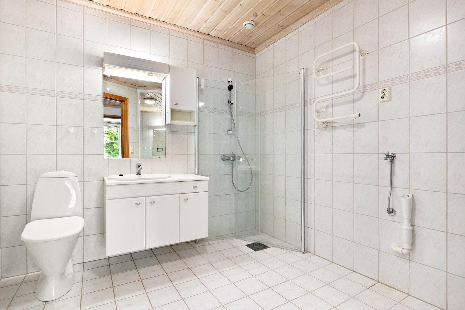 Flislagt bad med varmekabler. Badet har gode oppbevaringsmuligheter i overskap og det er opplegg for vaskemaskin/tørketrommel. Galleribilde