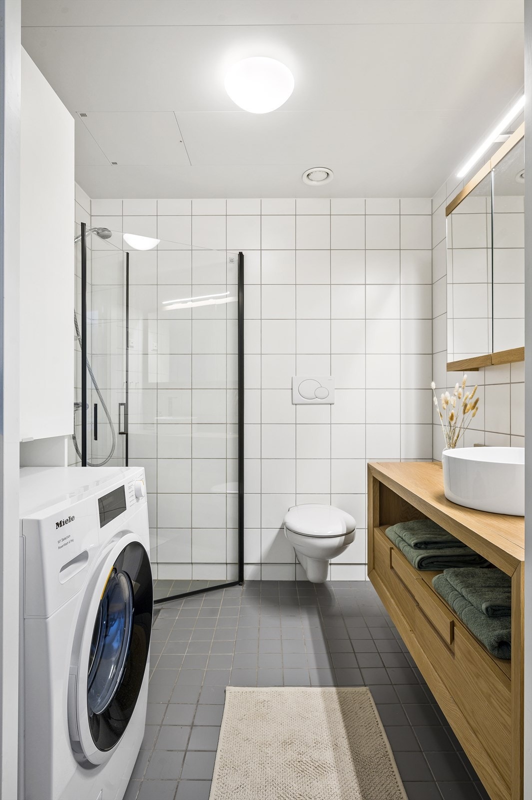 Romslig baderom med opplegg for vaskemaskin. Innfellbare dusjdører i herdet glass. Galleribilde