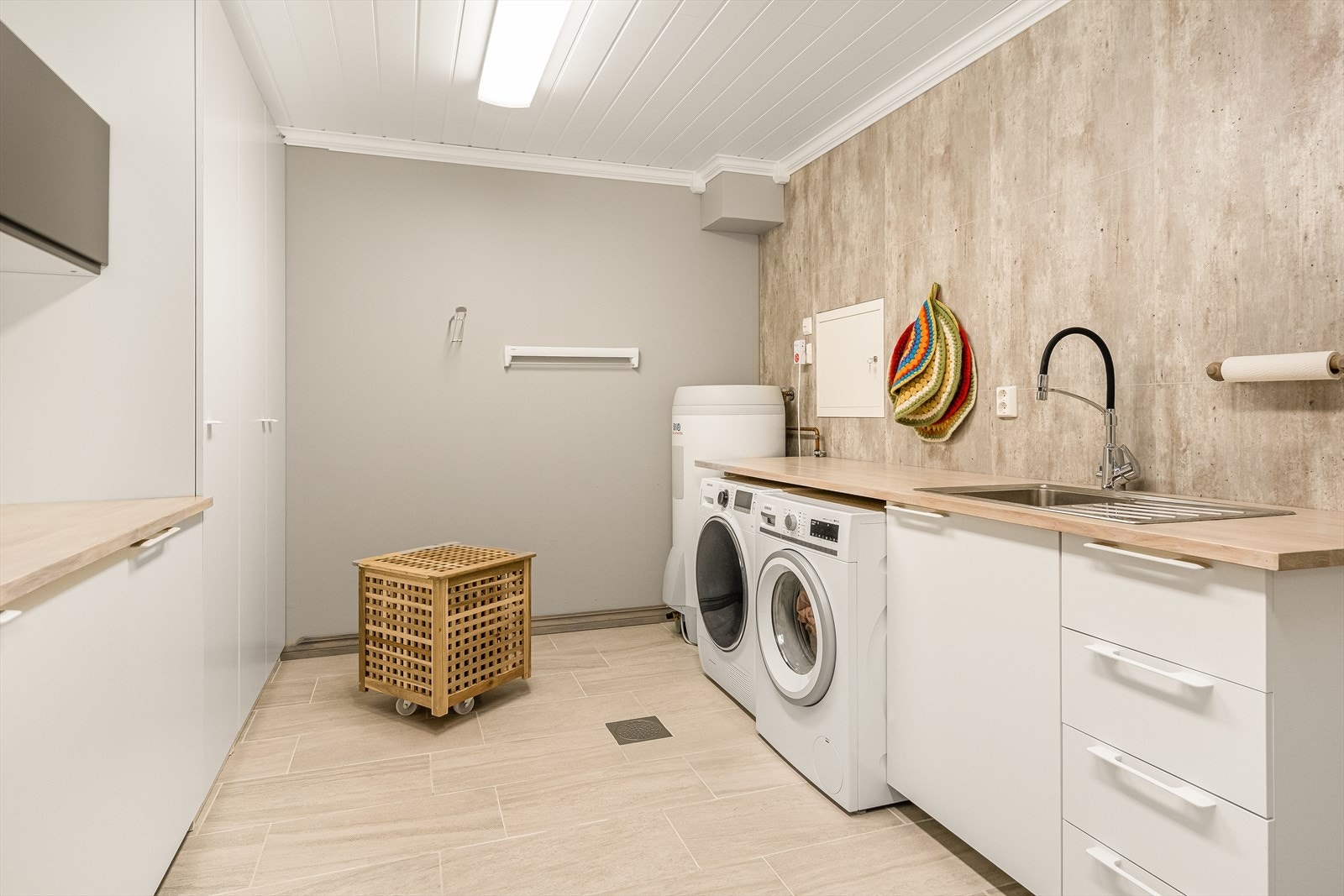 Vaskerommet har en romslig innredning med arbeidsbenk og stål vaskekum og plass til vaskemaskin og tørketrommel. Her er det samlesentral for rør i rø og sikringsskap. Galleribilde