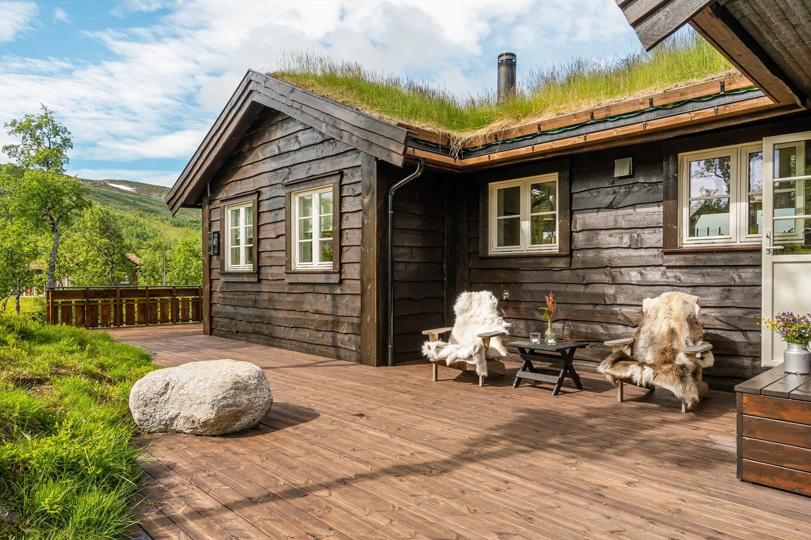 Stor terrasse som strekker rundt store deler av hytten. Galleribilde