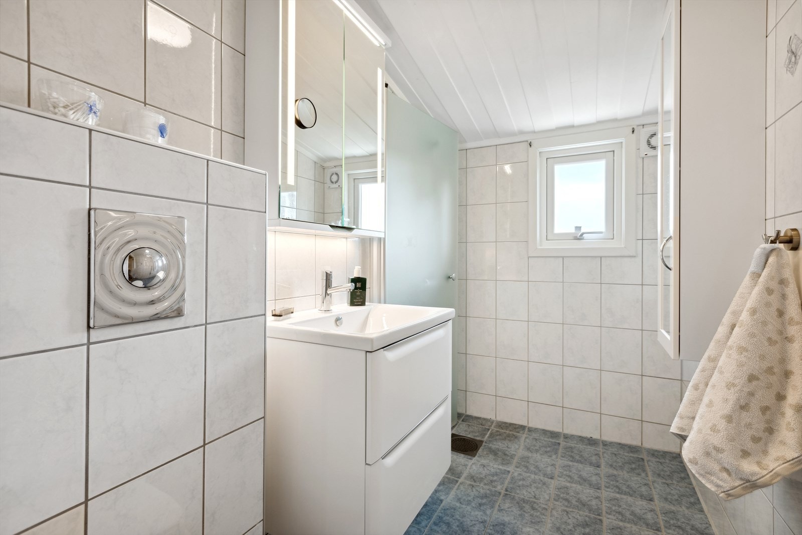 Badet er innredet med vegghengt wc, dusj, servantinnredning og speil med integrert lysarmatur Galleribilde