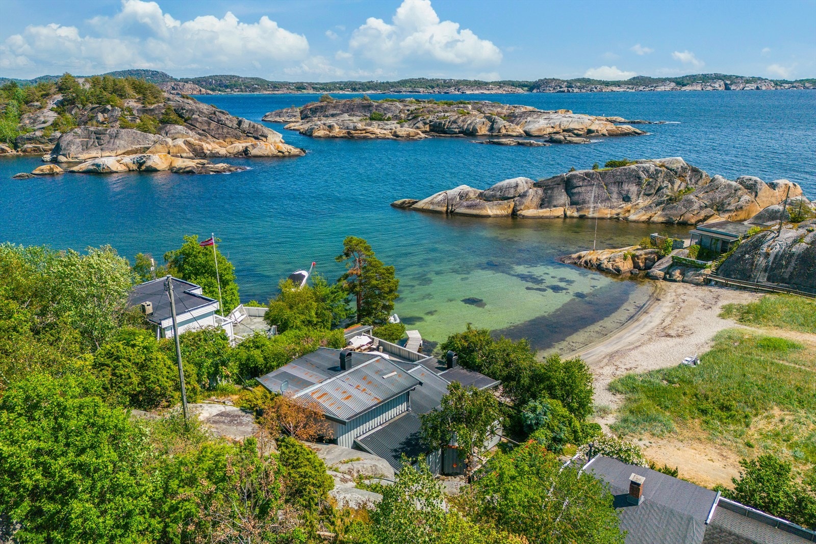 Hytta ligger skjermet til i Skjellsand, en liten bukt med sandstrand, ytterst i Håkavika Galleribilde