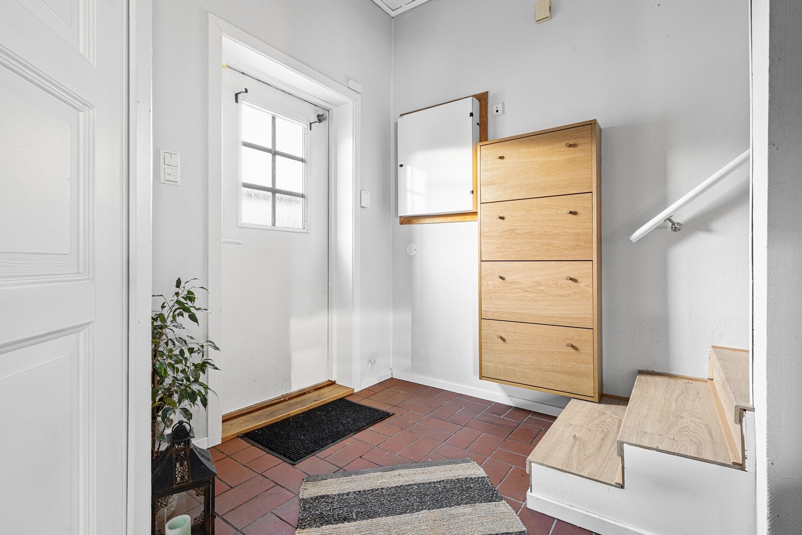 Entre med fliser på gulv, garderobeskap og gjestetoalett til venstre. Galleribilde