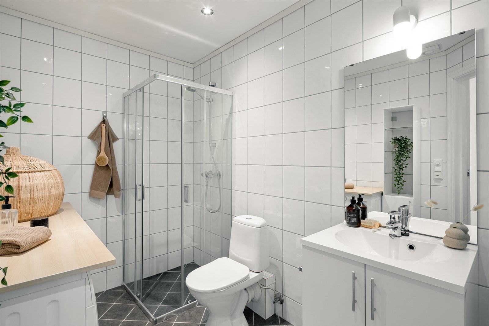 Lyst og tidløst bad med flislagte vegger, malt himling, downlights i tak og varmekabler i gulv. Galleribilde