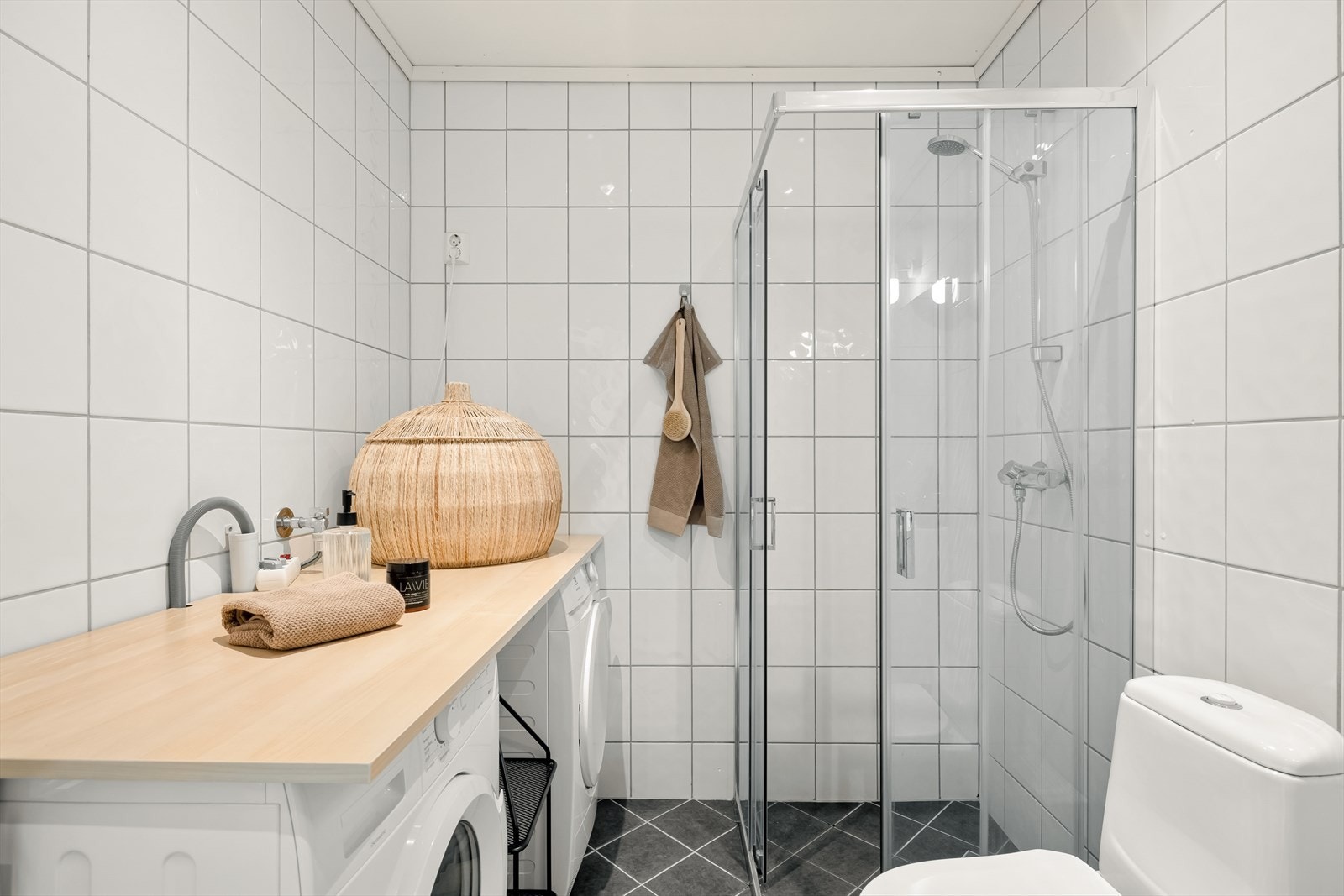 Innredet med servant m/speil og belysning, toalett, dusjhjørne og en egen vaskeromsløsning med benkeplate. Galleribilde