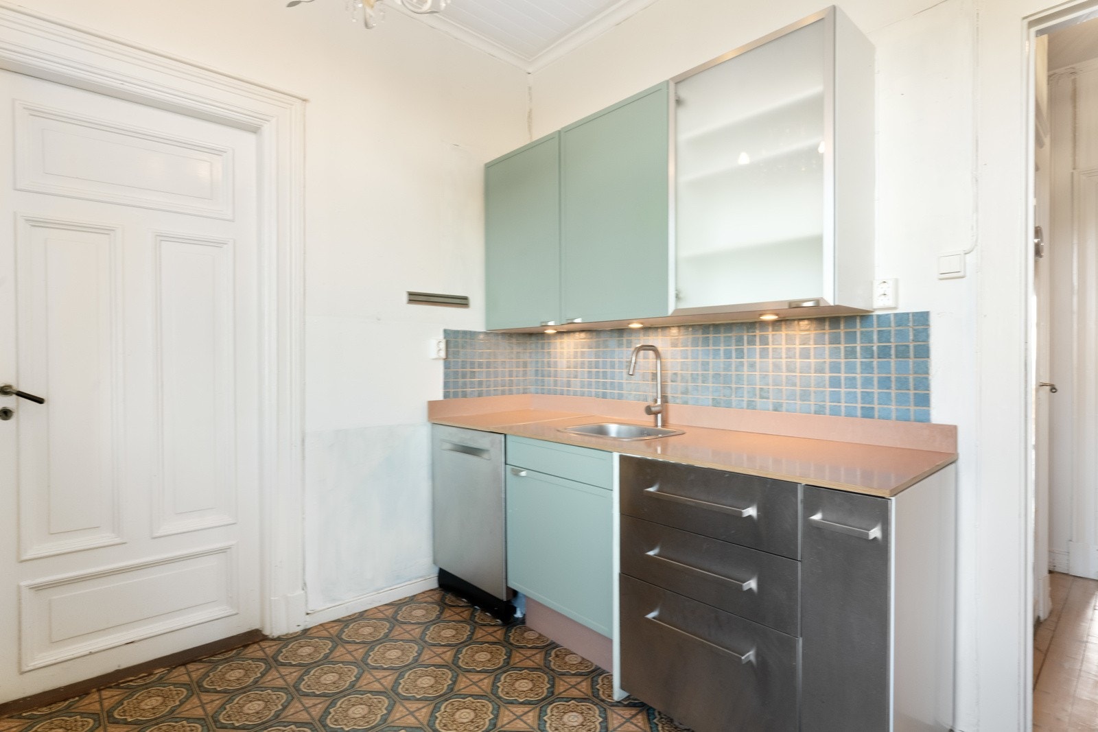 Benkeplaten er i trefarget laminat og har nedfelt oppvaskkum i stål. Over oppvaskkummen er det benkebelysning. Kjøkkenet har plass til komfyr og kjøleskap, samt opplegg for oppvaskmaskin. Galleribilde