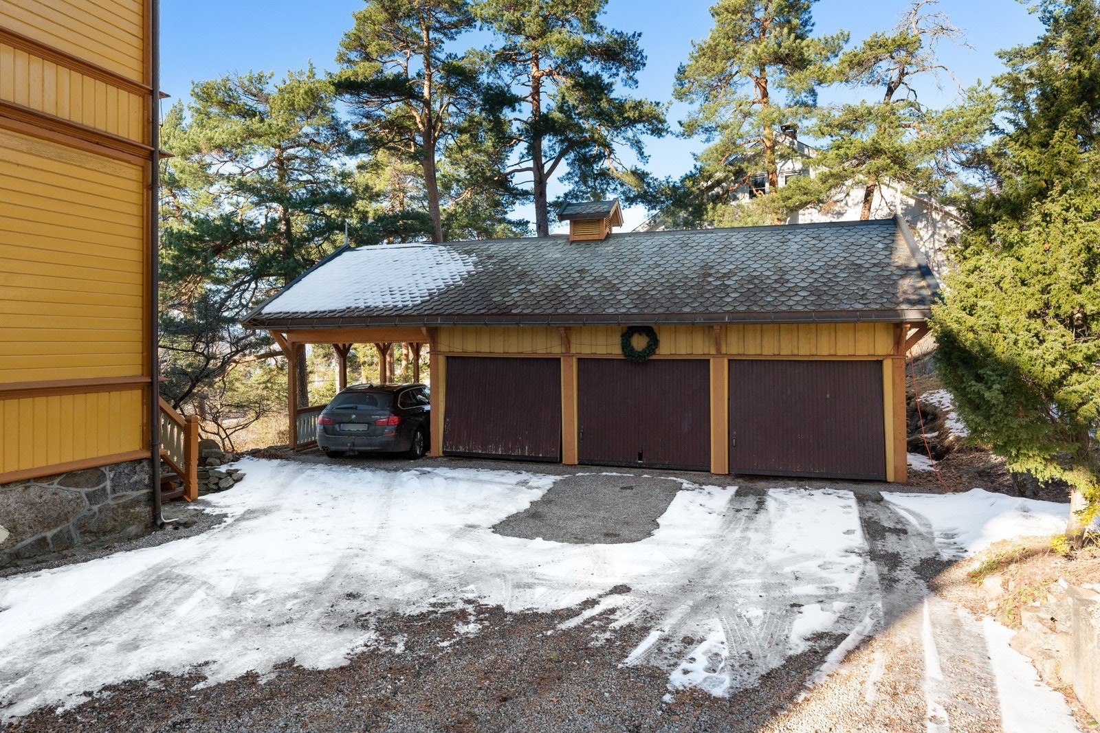Det er gode parkeringsmuligheter på gruslagt gårdsplass og i et garasjebygg med tre garasjer og en carport. Galleribilde