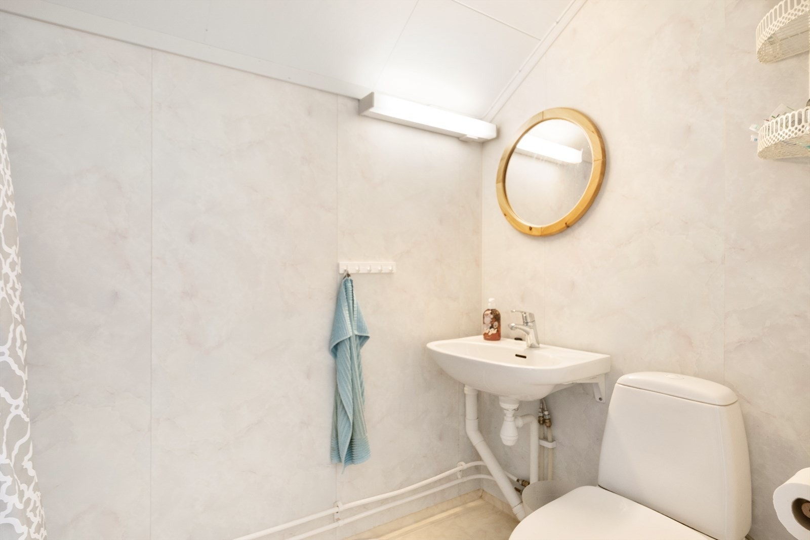 Bad i 2.etasje innredet med servant på vegg, toalett og dusjkabinett med forheng. Galleribilde