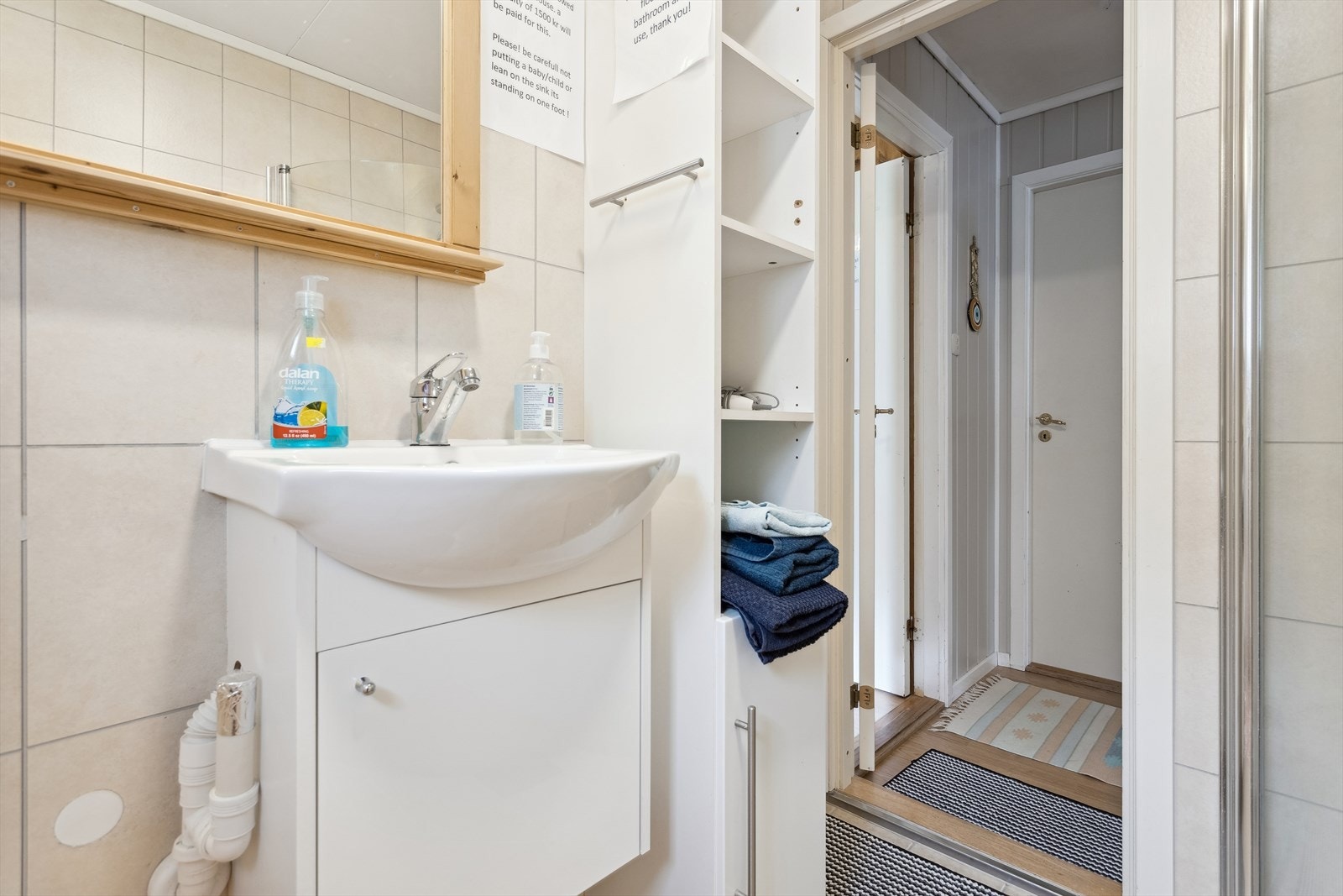 Badet er innredet med dusjvegger av glass, toalett, servant, speil og skap/hyller Galleribilde