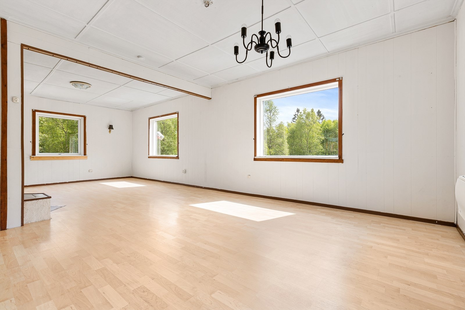 Romslig stue i 1.etg. med laminatgulv og malte panelplater på vegger Galleribilde