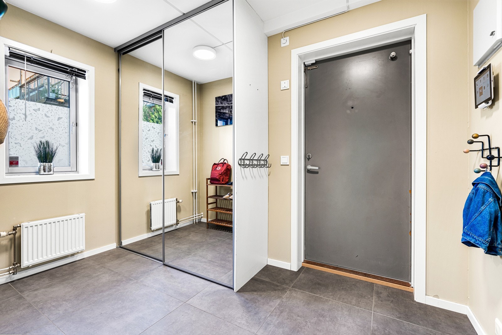 Leiligheten tar deg imot i en romslig entré med flislagt gulv over varmekabler. Her er det innredet med en stor skyvedørsgarderobe. Galleribilde