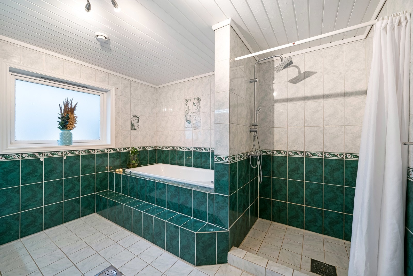 Badet har fliser på gulv og vegg og plass til både badekar og dusj. Galleribilde