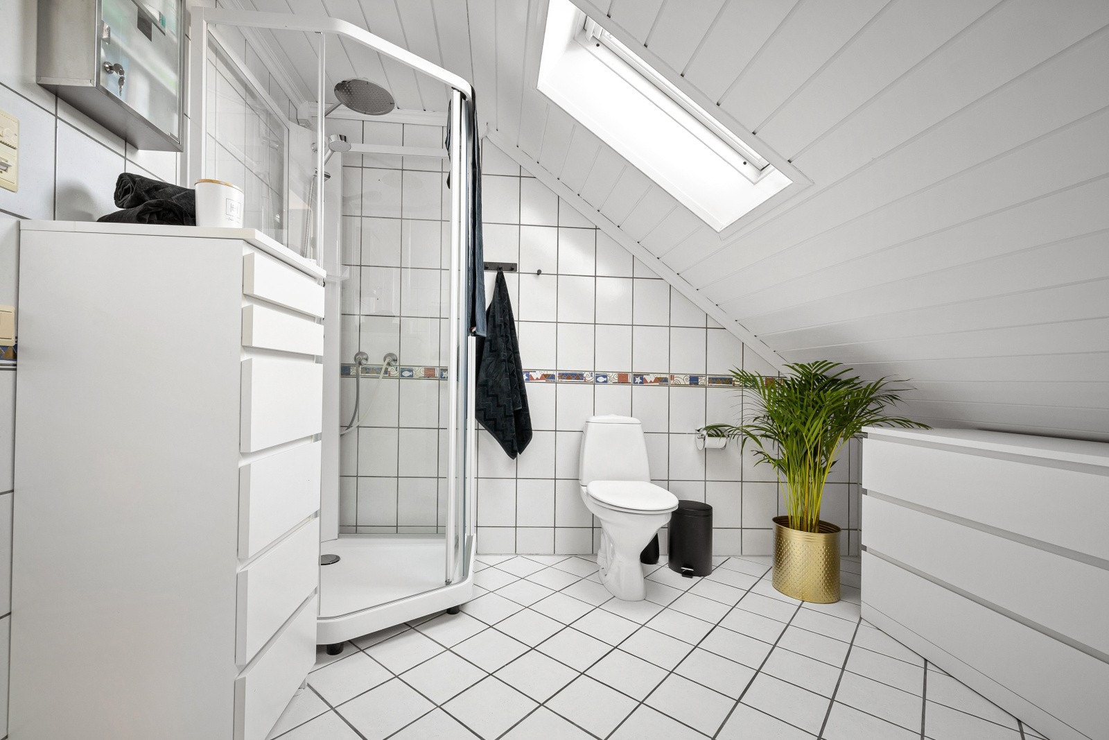 Badet er innredet med skapinnredning med profilerte, gråtonede fronter, laminert benk, to servanter samt overhengende speil og belysning. Galleribilde