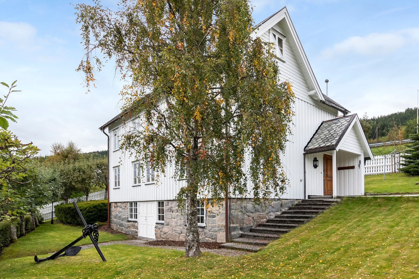 Tomten er opparbeidet med plenareal, prydbusker og gruset vei/parkering Galleribilde