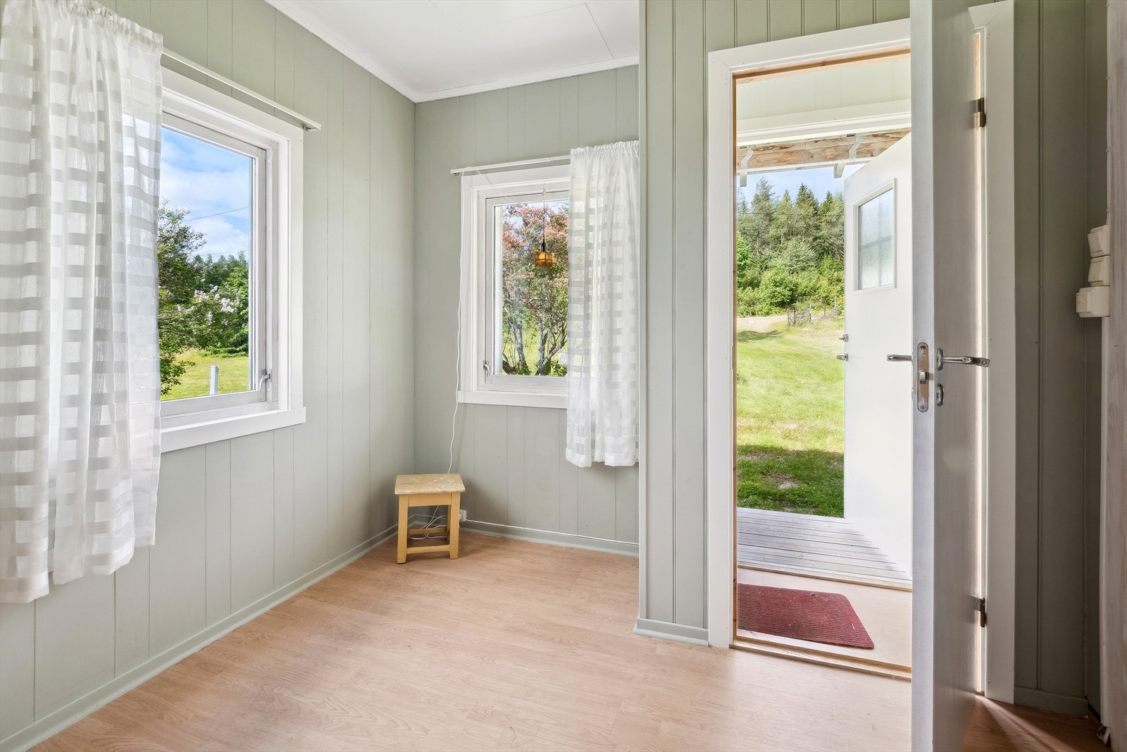 Du ønskes velkommen inn i et praktisk vindfang med videre adkomst til en romslig gang. Gangen har belegg på gulv, overflater malt i en innbydende farge og to vindusflater som slipper inn fint lys. Plass til garderobeløsninger etter eget ønske og behov. Galleribilde