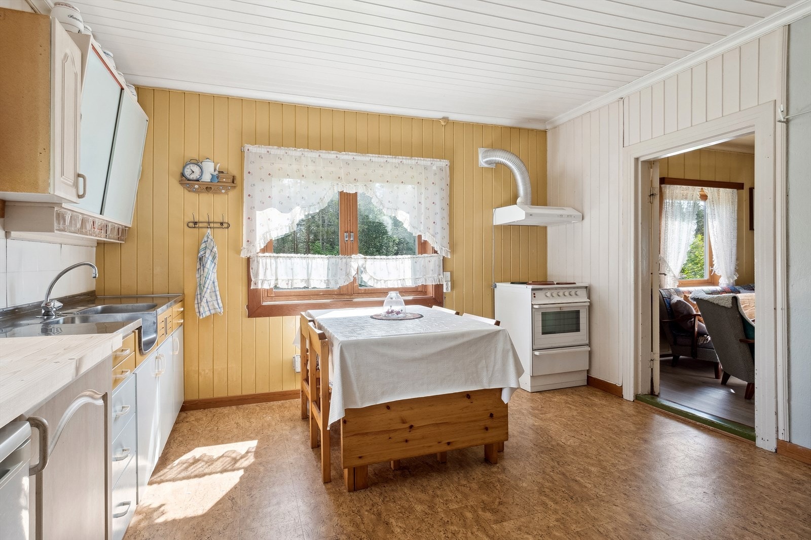 Boligen har et lyst og romslig kjøkken med belegg på gulv og lysmalt panel på veggene med en fin kontrastvegg. Galleribilde