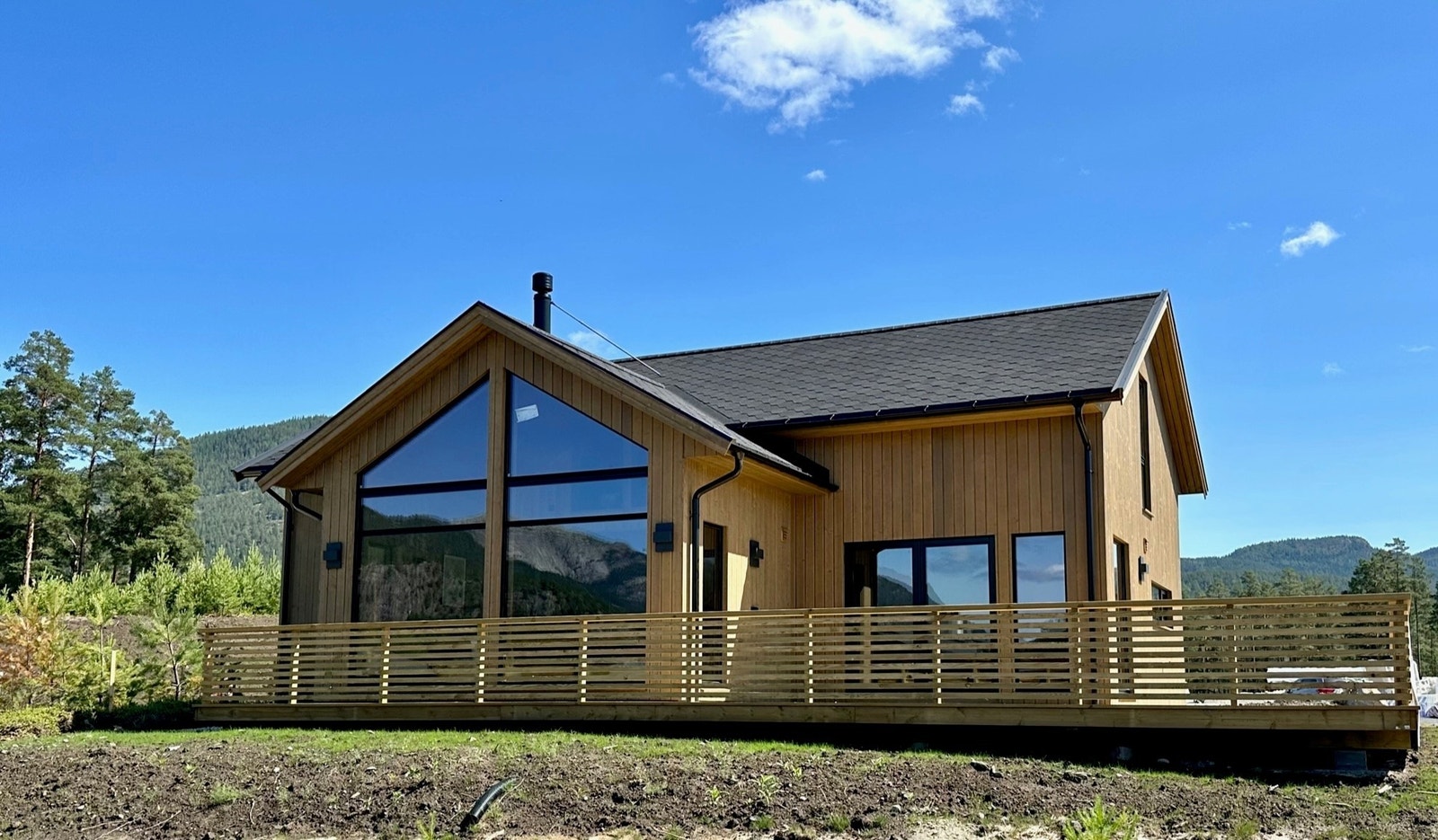 Store fine vinduer i front med stor terrasse - hytta ligger litt høyre en de andre hyttene i området. Galleribilde