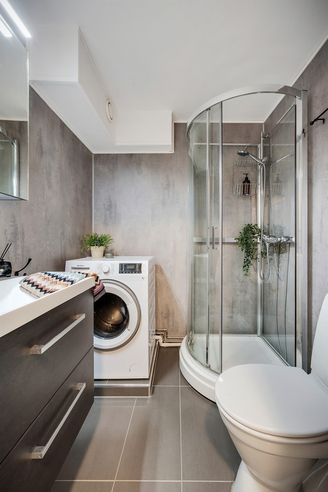 - Badet er innredet med benkeskap med servant, dusjkabinett, gulvmontert toalett og opplegg for vaskemaskin - Galleribilde