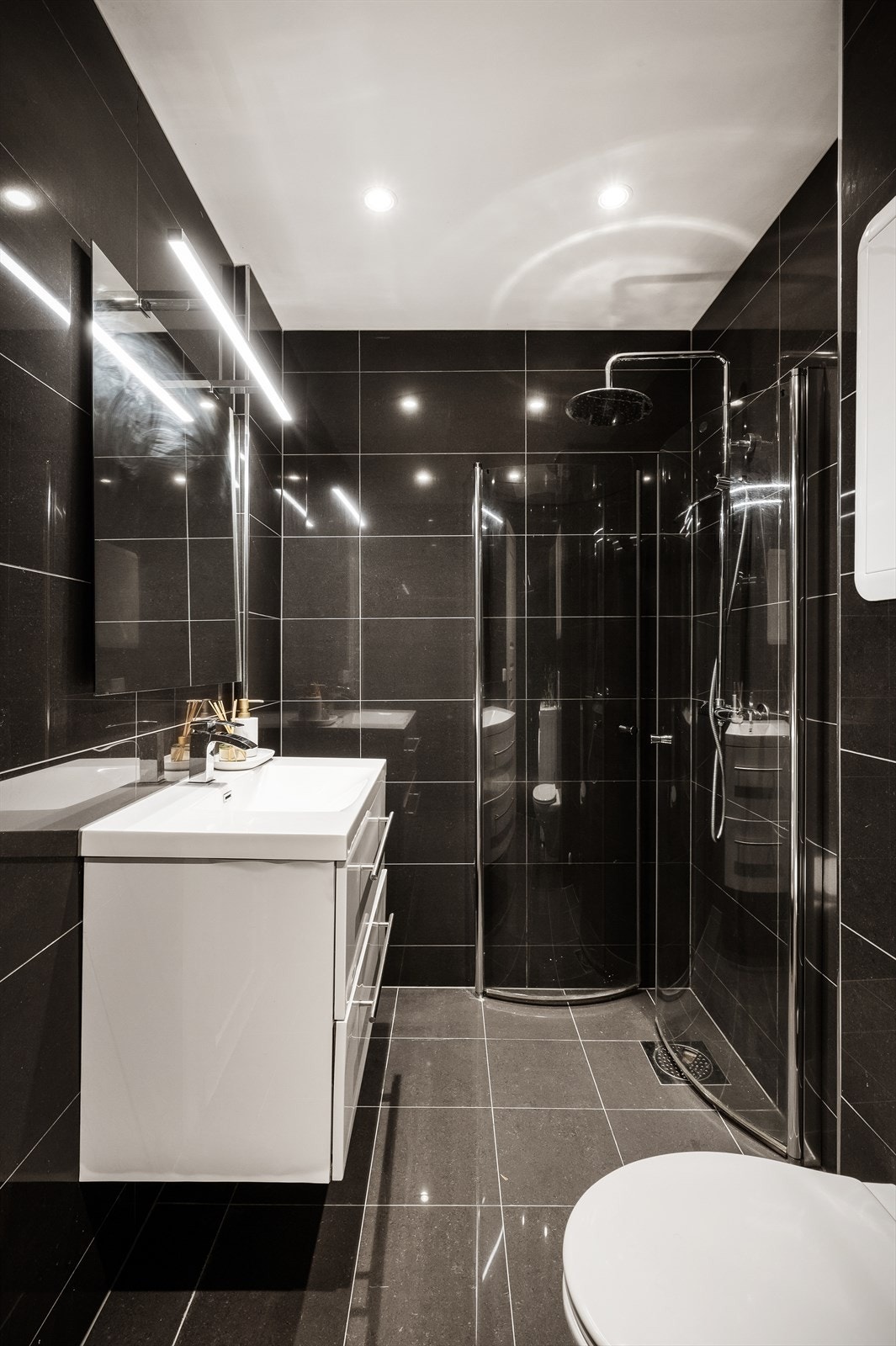 - Moderne helfliset bad innredet med benkeskap med servant, dusjdører i glass, vegghengt toalett, og vaskemaskin - Galleribilde