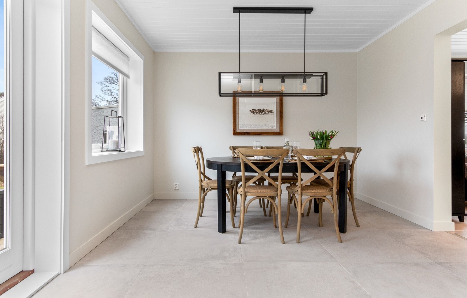 Her er det lagt store, grå gulvfliser med varme, som bidrar til en flytende overgang mellom rommene. Galleribilde