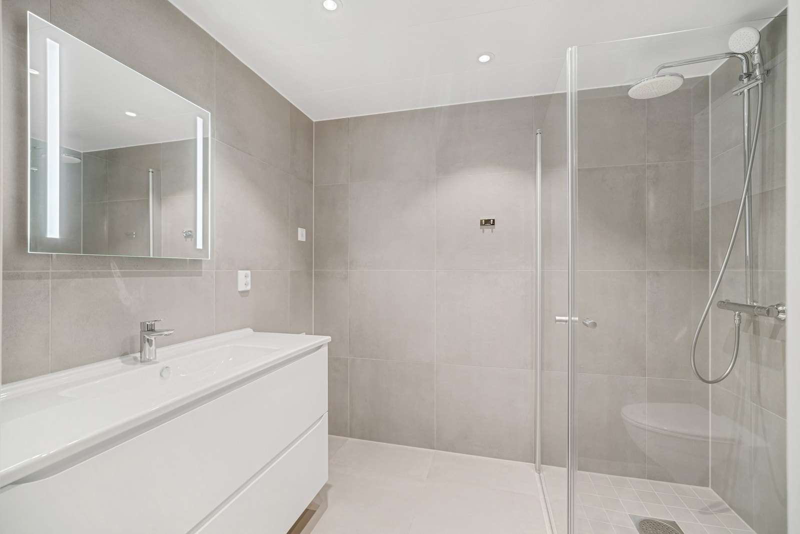Moderne flislagt bad med downlight-belysning i tak. Galleribilde