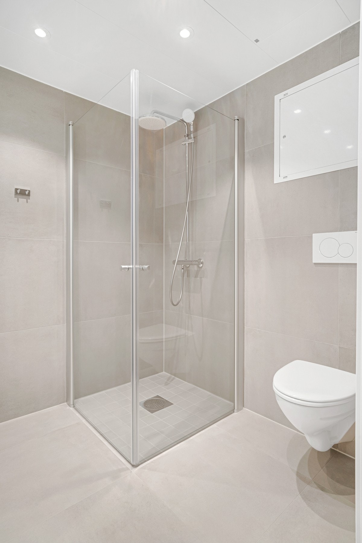Badet har store grå 60x60 cm flis på vegg og gulv, og 10x10 cm flis i nedsenket dusjnisje. Galleribilde