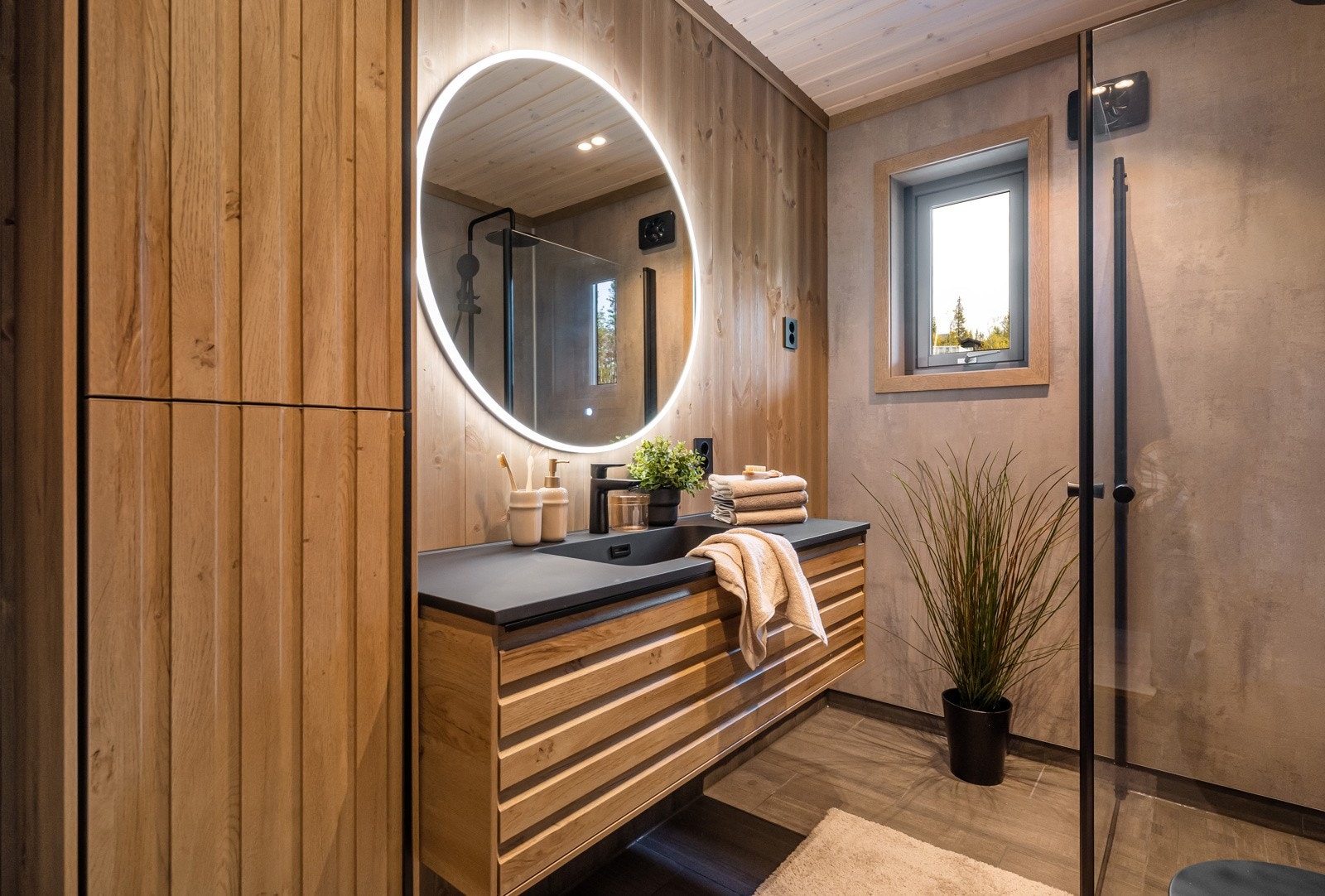 Badet er innredet med dusjsone med foldedører, servantskap med skuffer og vegghengt toalett. Galleribilde