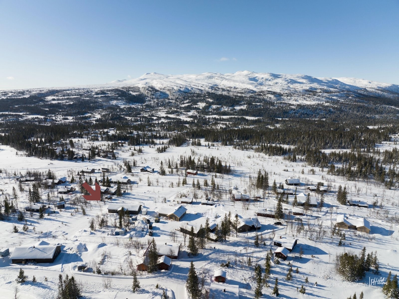 Oversiktsbilde av hyttefeltet, hytta ligger litt til venstre for midten av bildet. Galleribilde