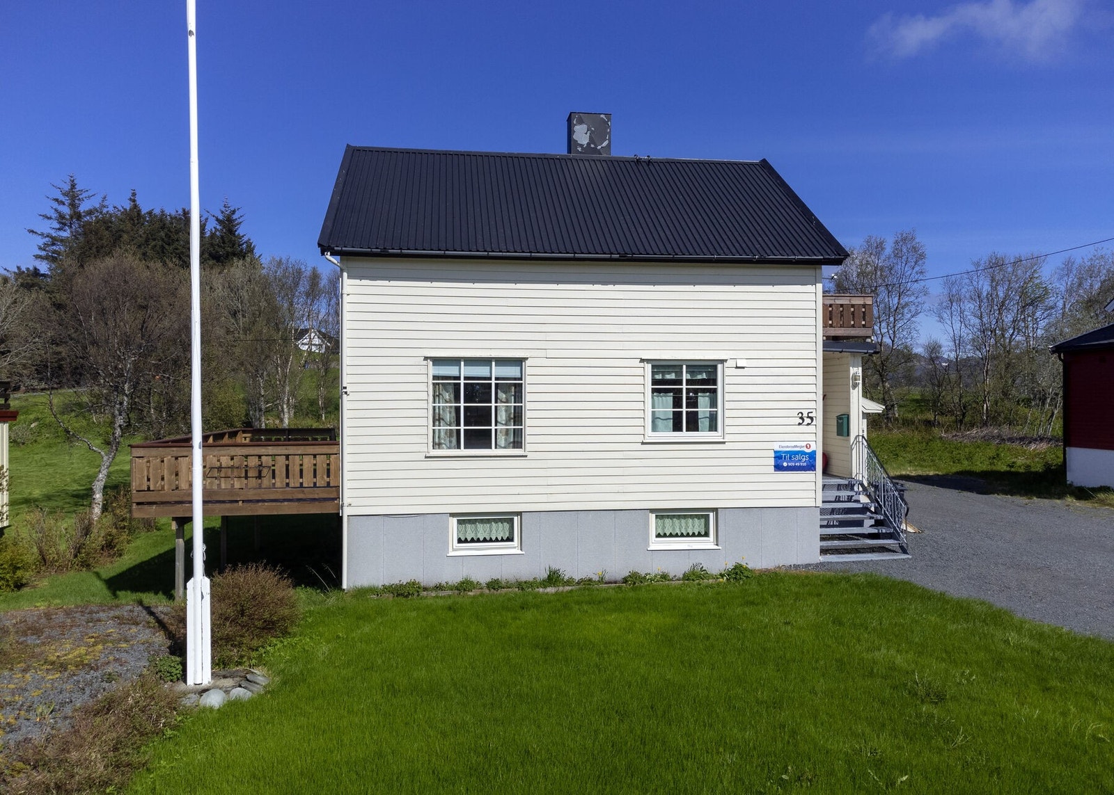 Uteområdet er pent opparbeidet med plen, flaggstang og enkel beplantning Galleribilde