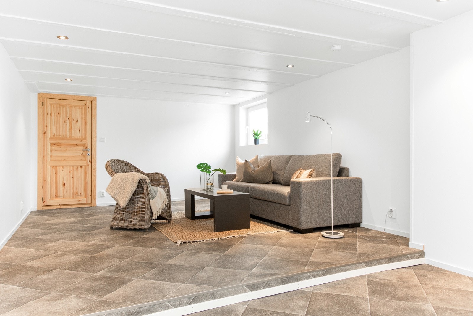 Eneboligen har en stor og meget trivelig kjellerstue over to nivåer med gulvbelegg og hvitmalte overflater som gjør det enkelt å innrede etter egen smak og stil. Galleribilde