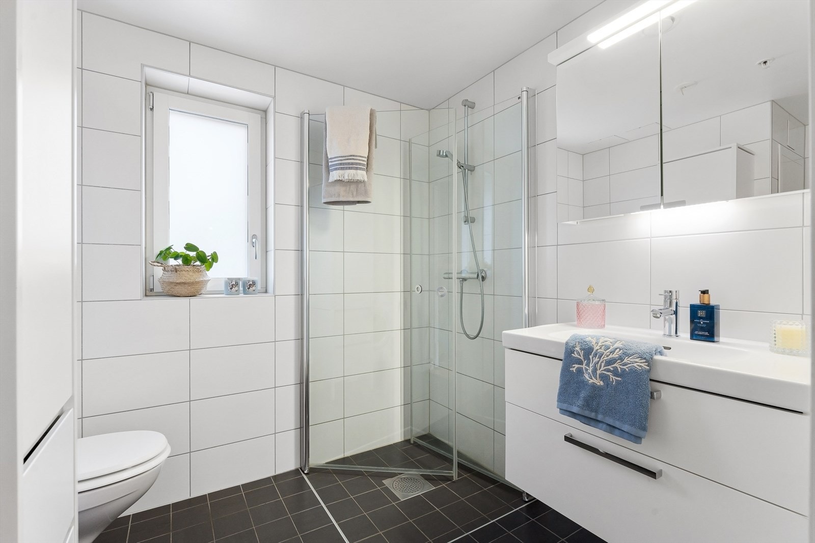Pent og romslig flislagt baderom med gulvvarme og opplegg for vaskemaskin. Galleribilde