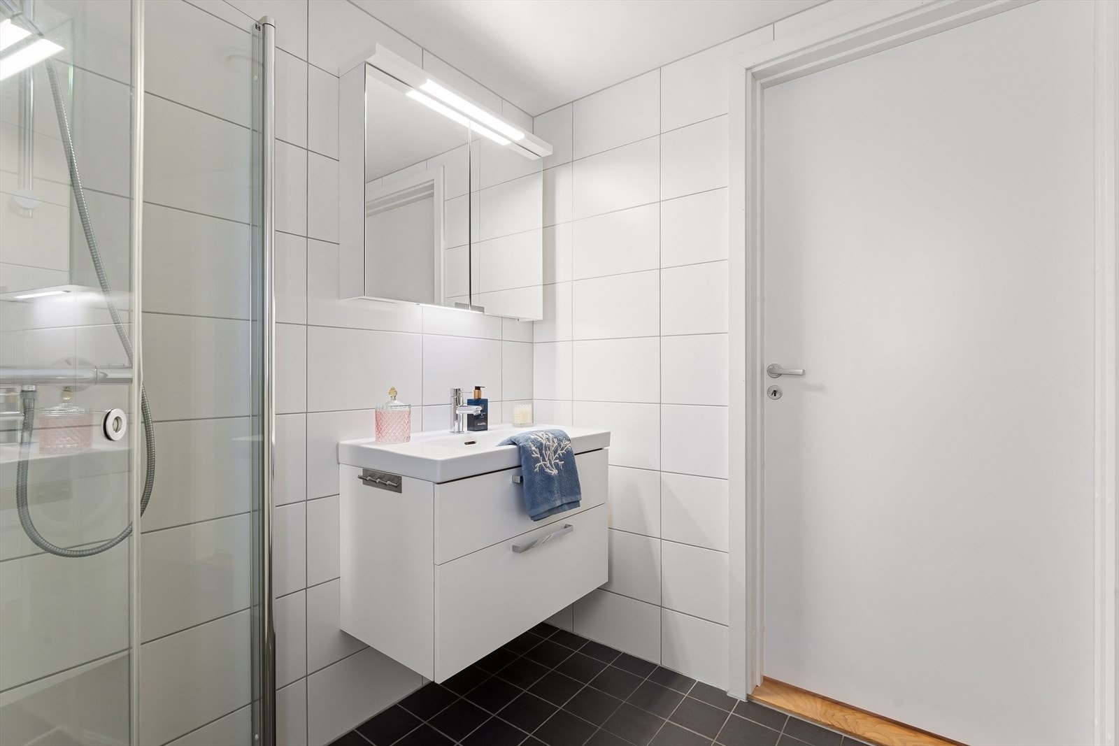 Badet er innredet med vegghengt servantskap, servant med ett-greps armatur, dusjhjørne med to-greps armatur og dusjdører i glass samt vegghengt toalett. Galleribilde