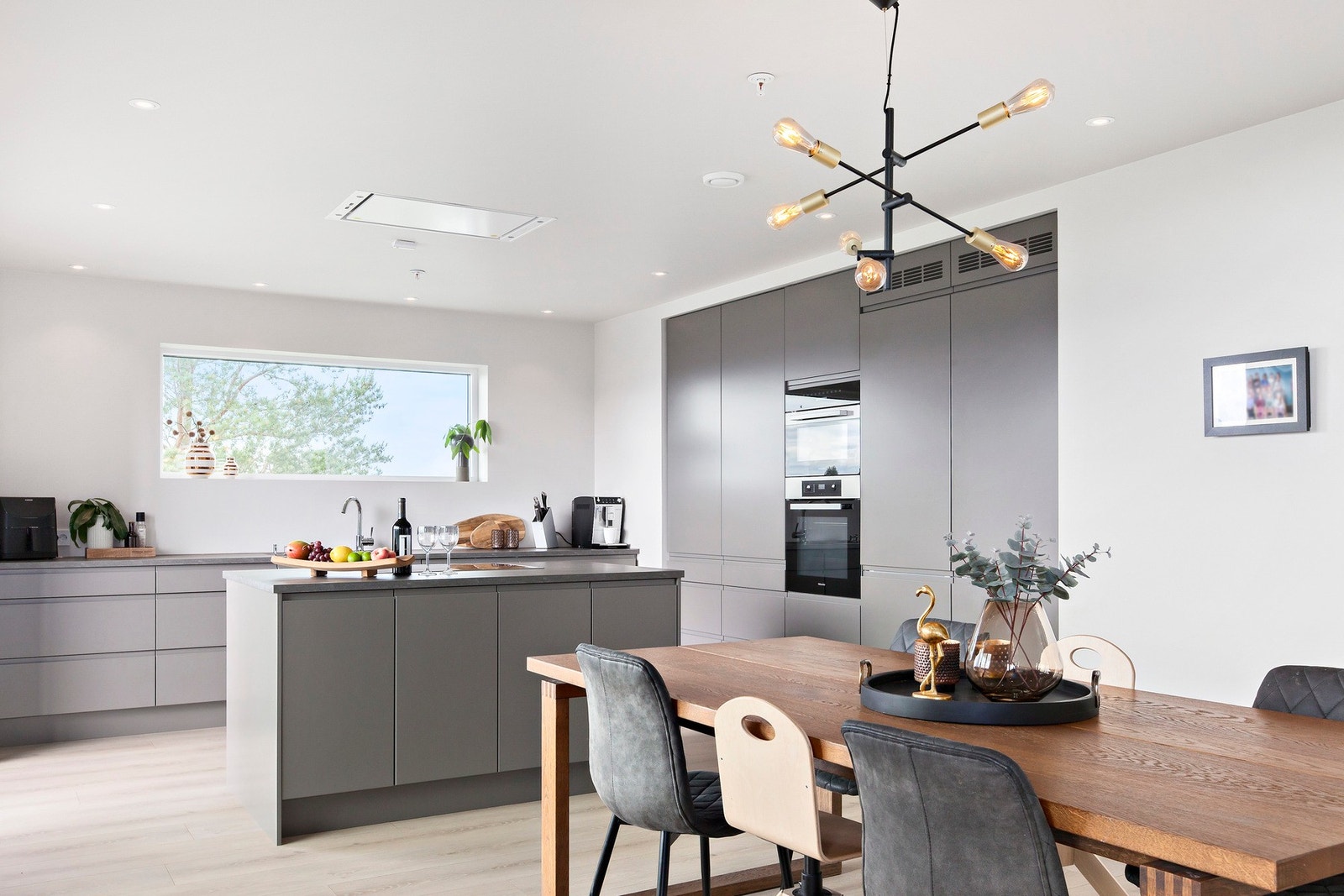 Stilfullt kjøkken med innebygde hvitevarer og ventilator i tak. Galleribilde