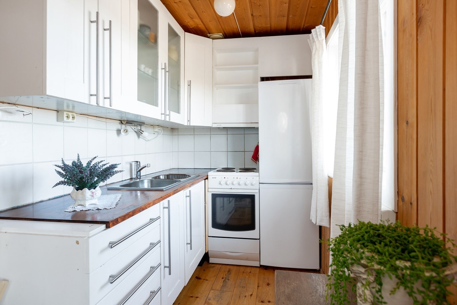 Lyst og hyggelig kjøkken. Kjøkkeninnredning består av skrog av plater og malte fronter. Galleribilde