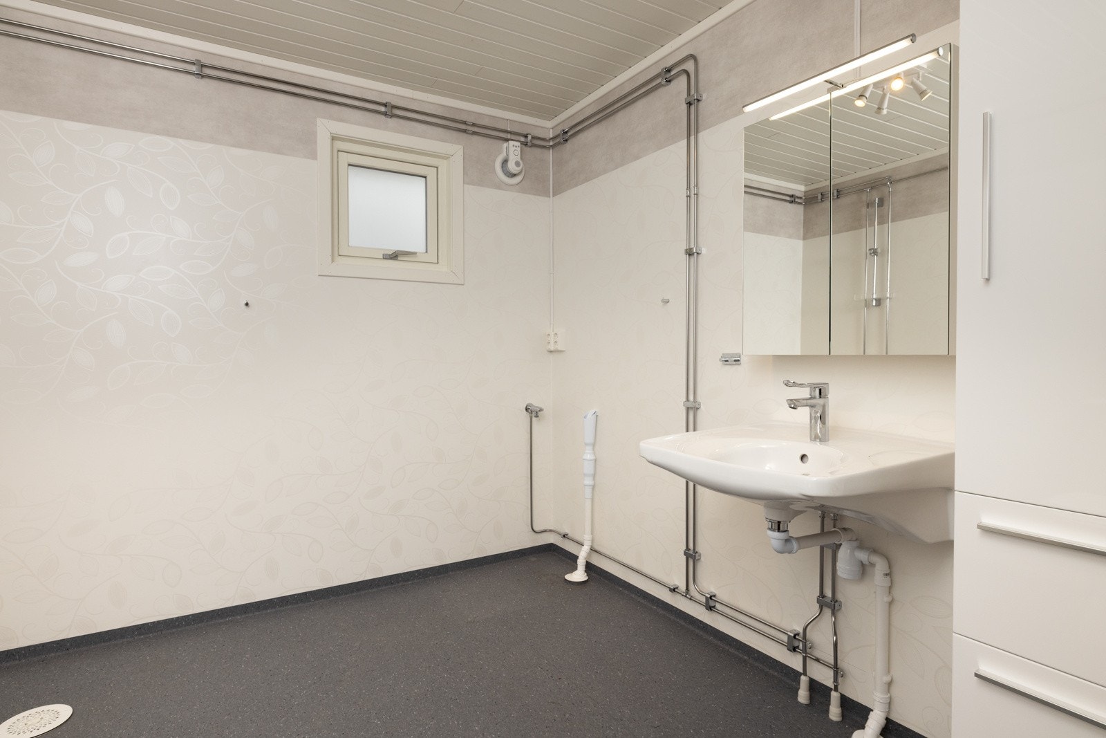 Bad i 1.etasje fra 2020 med servant på vegg, toalett og åpen dusj. Galleribilde