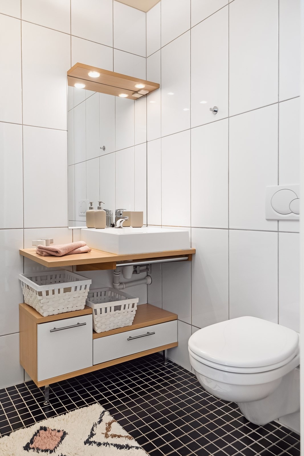 Videre er badet utstyrt med dusjhjørne, vegghengt toalett og servantskap med speil og lys. Galleribilde