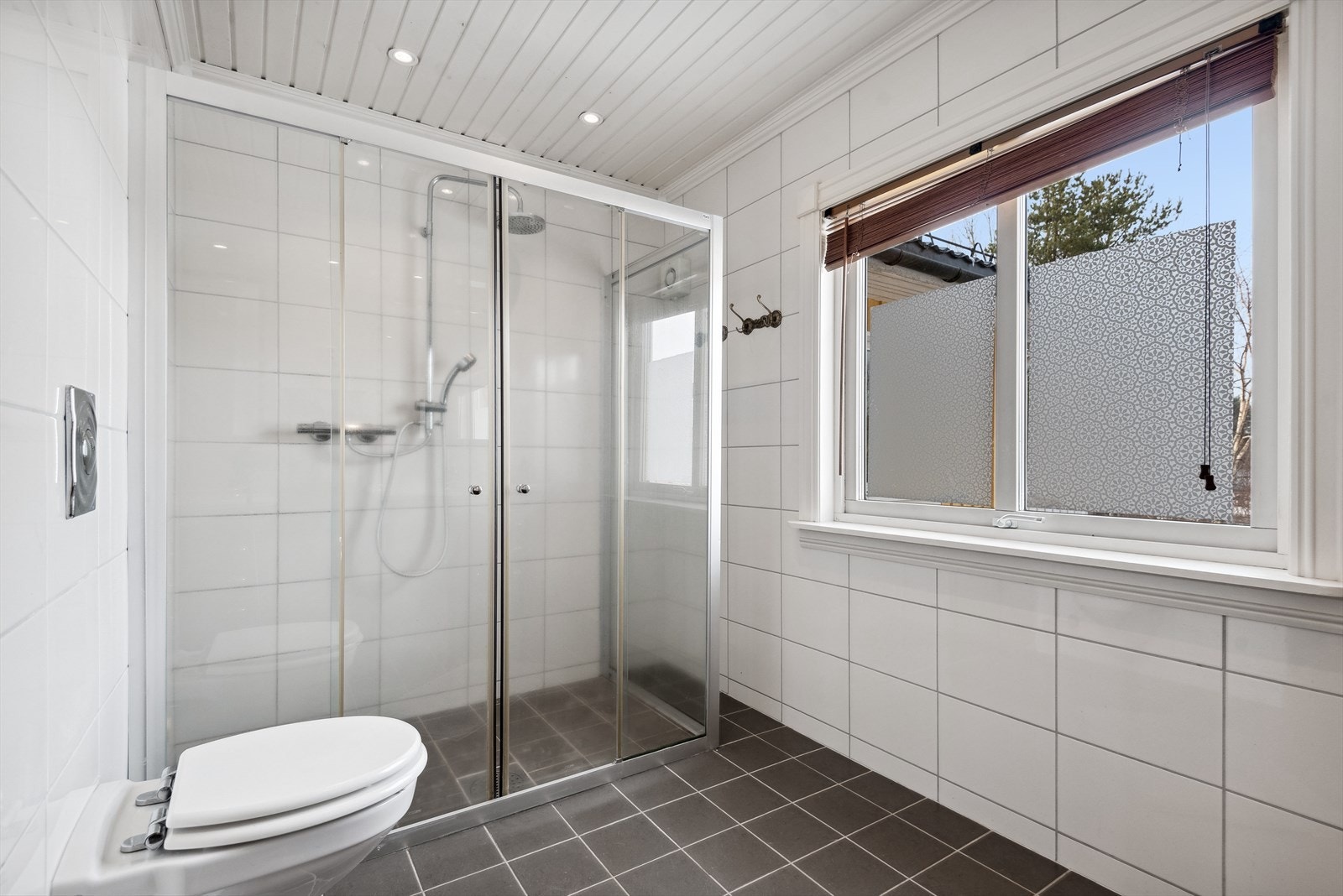 Her er det fliser på vegger, malt trepanel i himling og flislagt gulv med varmekabler. Galleribilde