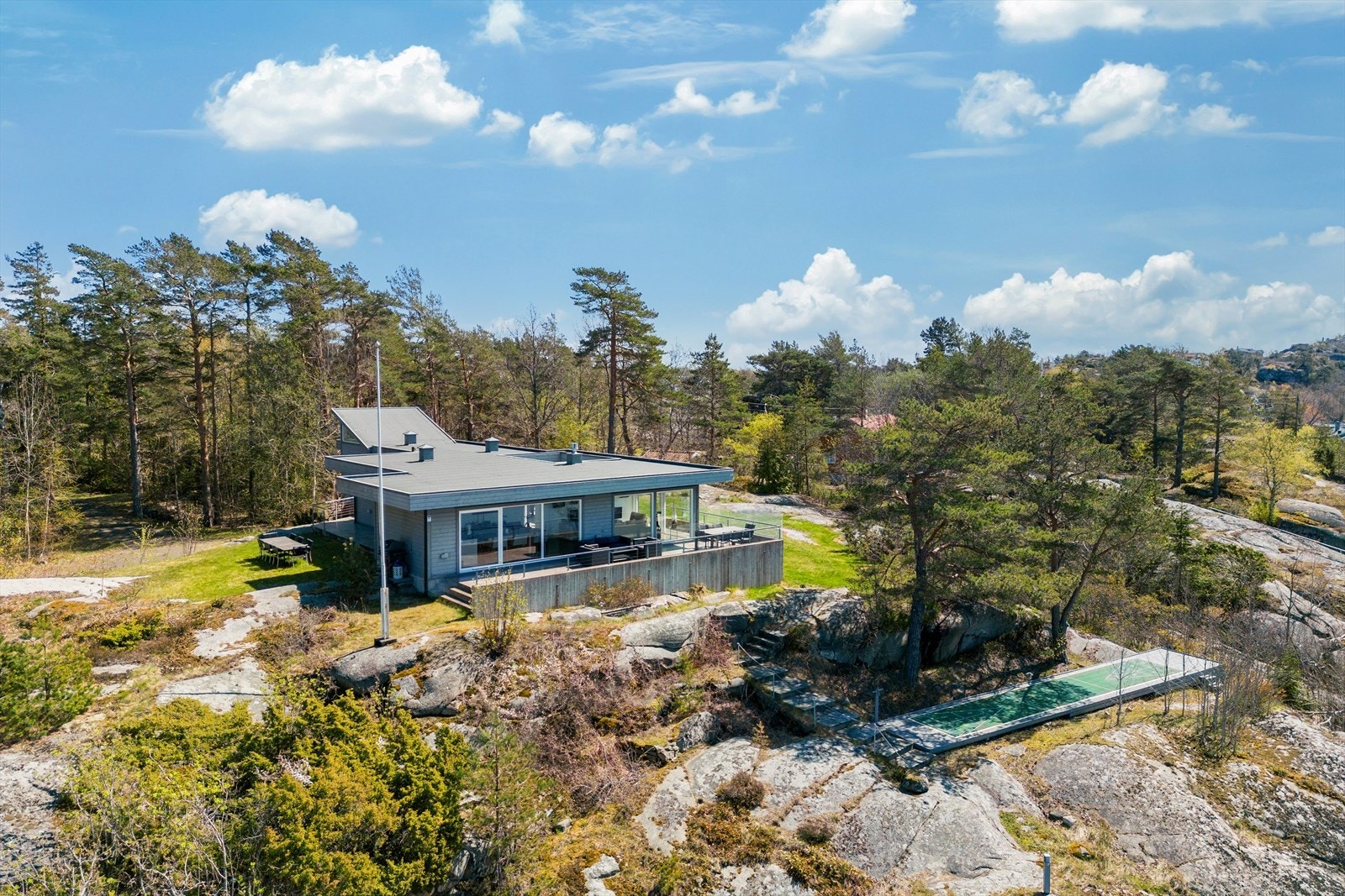 Fritidsboligen ligger omkranset av en tomt med svaberg, trær, gressarealer og vakker natur. Galleribilde