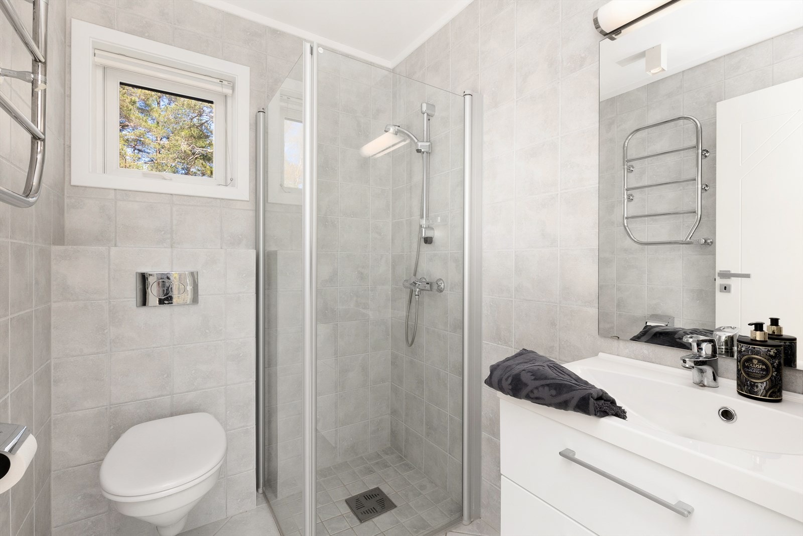 Badet i gjestedelen har veggmontert toalett, dusjhjørne og hvit innredning. Galleribilde