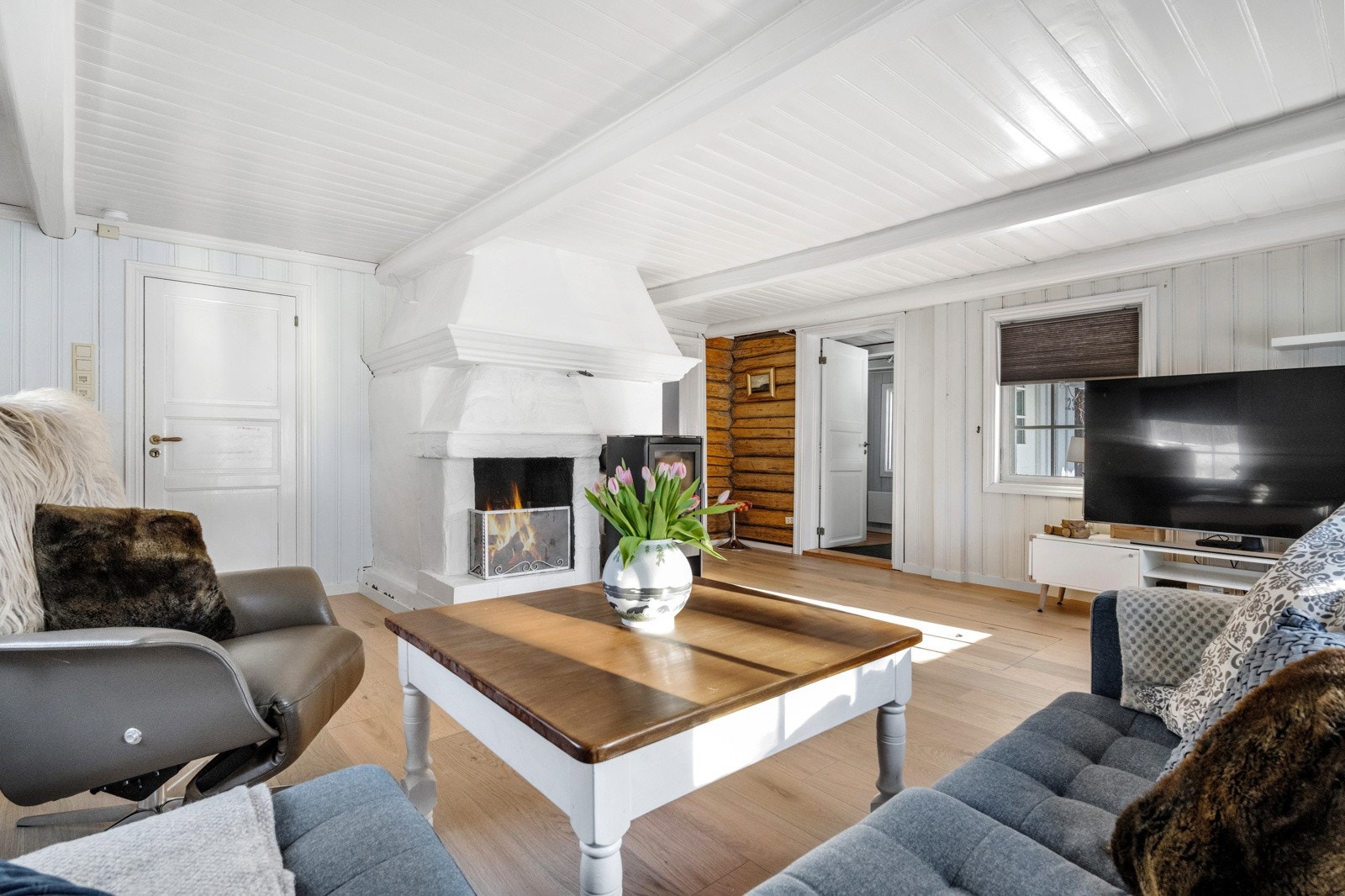 Lys og trivelig stue med fine innredningsmuligheter, hvor et hjørne har gamle tømmervegger Galleribilde