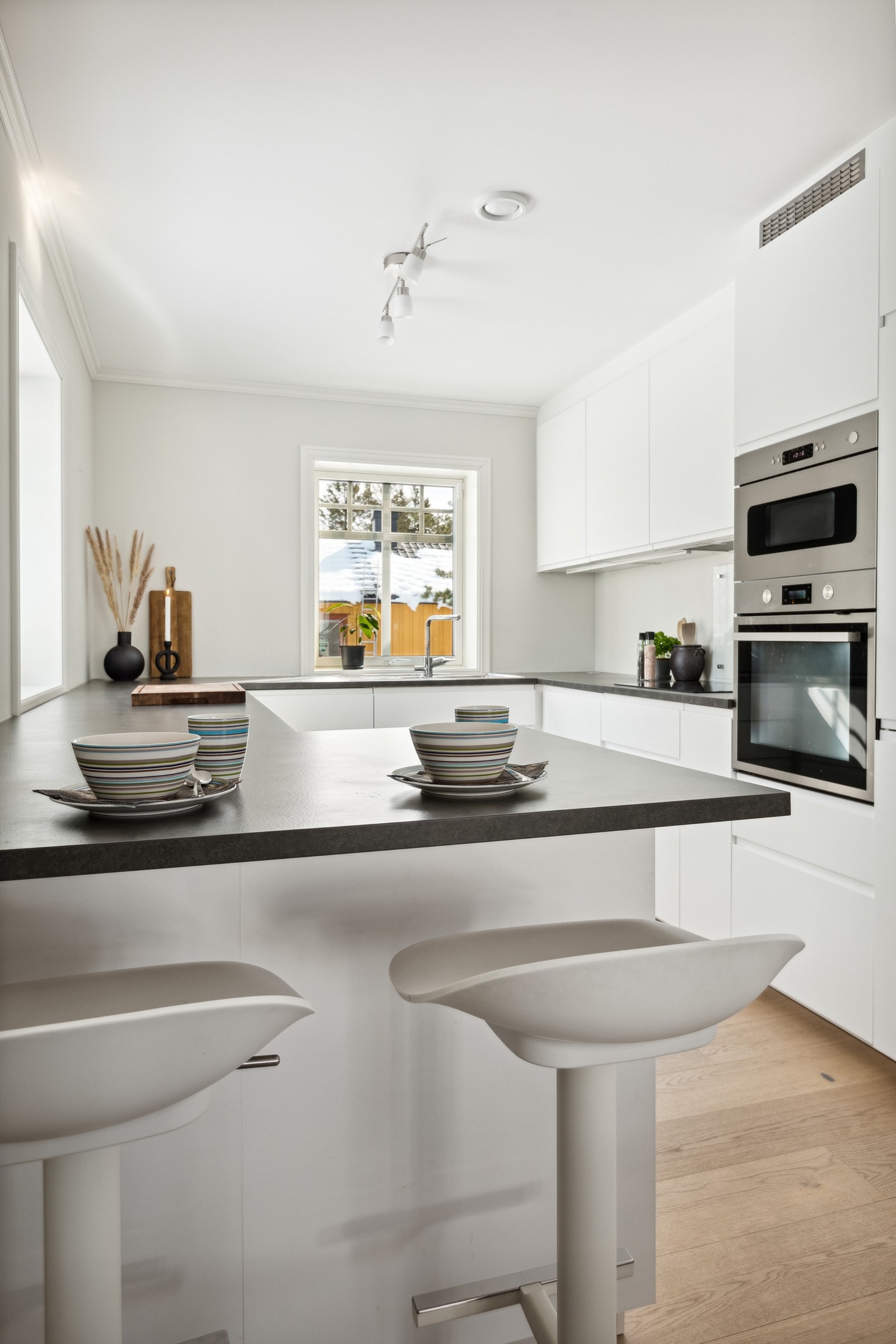 Moderne og stilren kjøkken i attraktiv kontrast med mye naturlig lys. Galleribilde