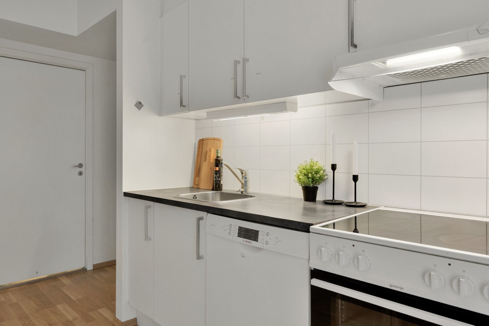 Det er montert belysning og hvite fliser over kjøkkenbenken. Galleribilde