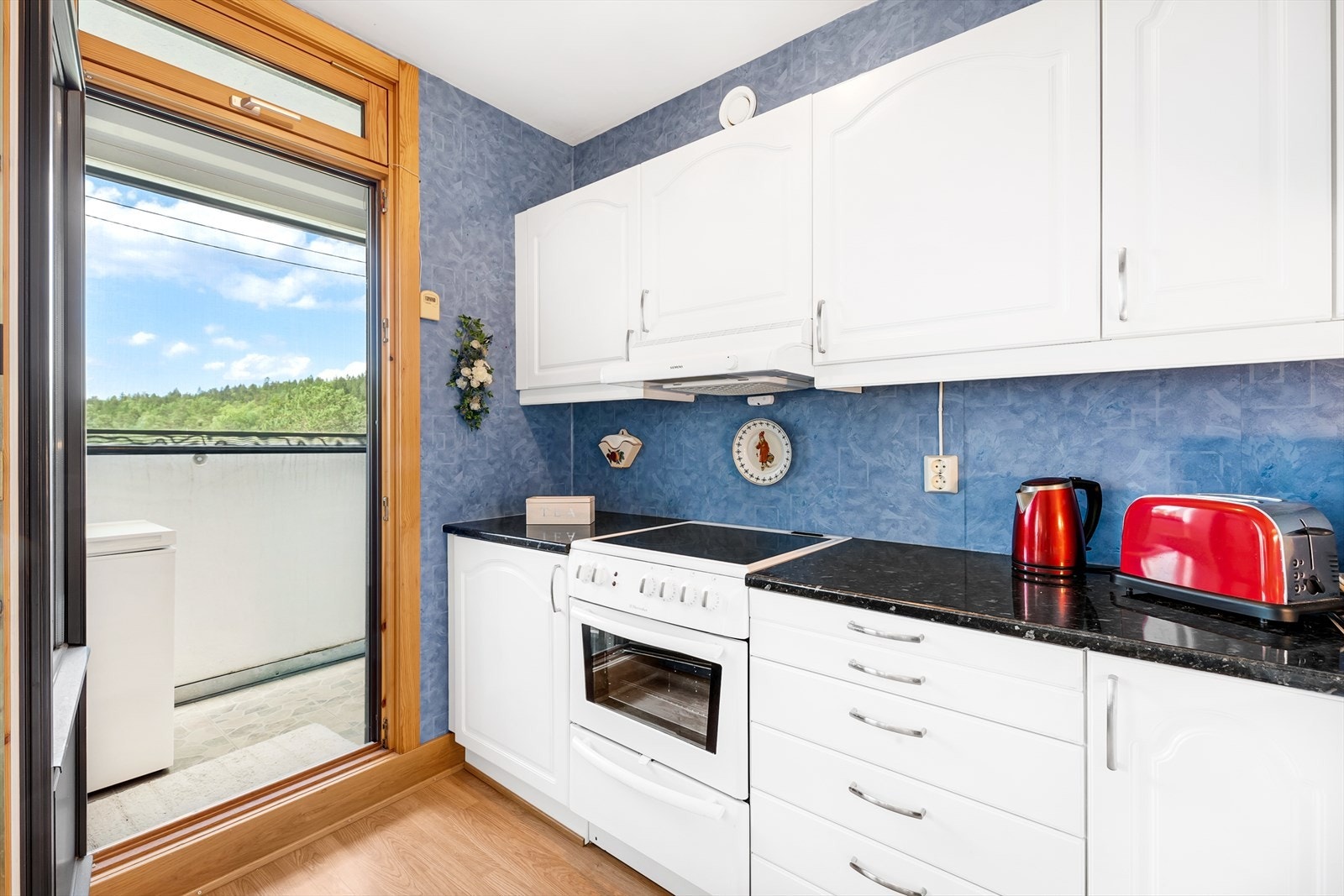 Kjøkken med laminat på gulv, tapet på vegger og malt tak. Det er utgang til en vestvendt lufte balkong på 2m² med solgardin. Galleribilde