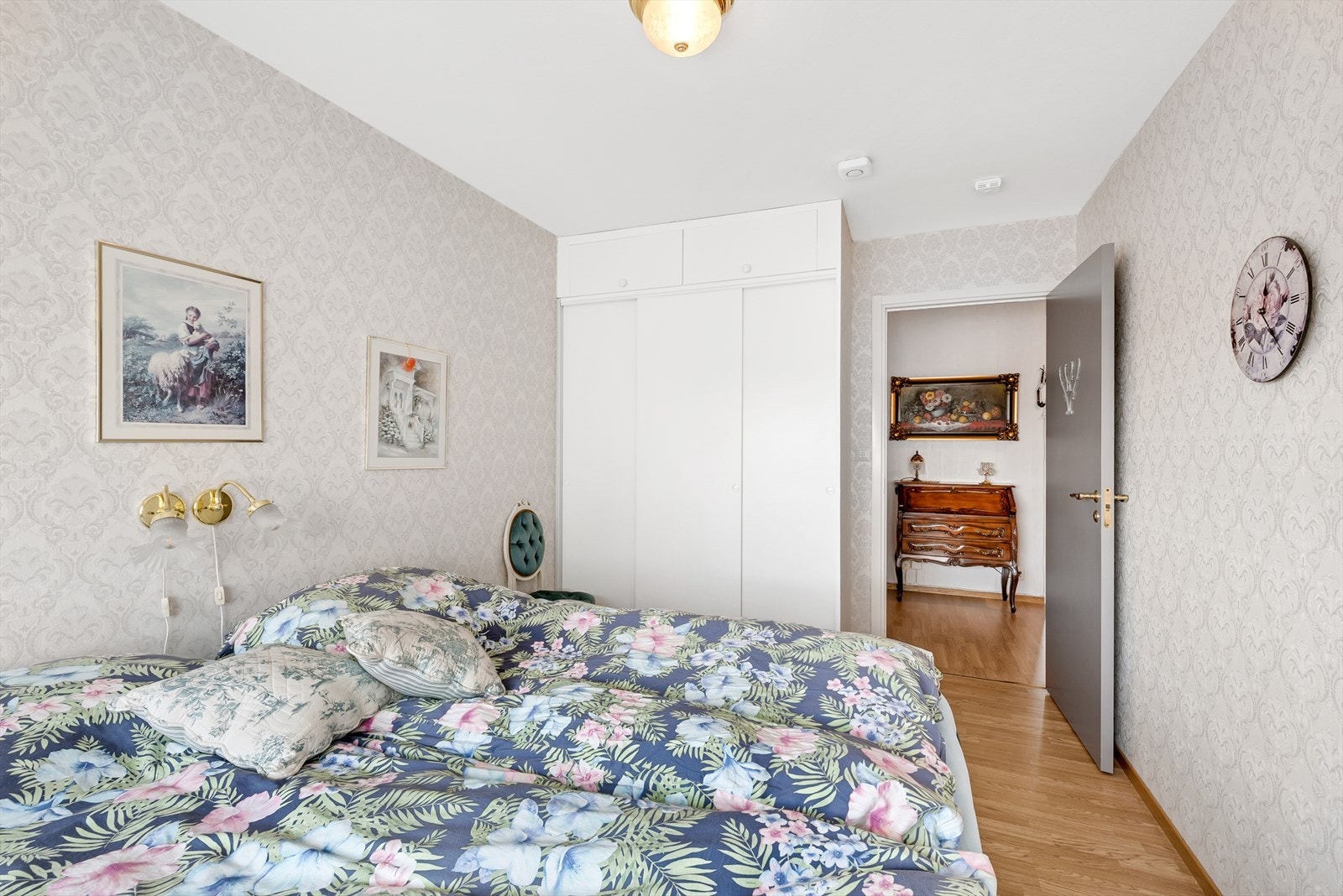 Soverom 1 med laminat på gulv, tapet på vegger og malt tak. Det er montert en plassbygd skyvedørsgarderobe. Galleribilde