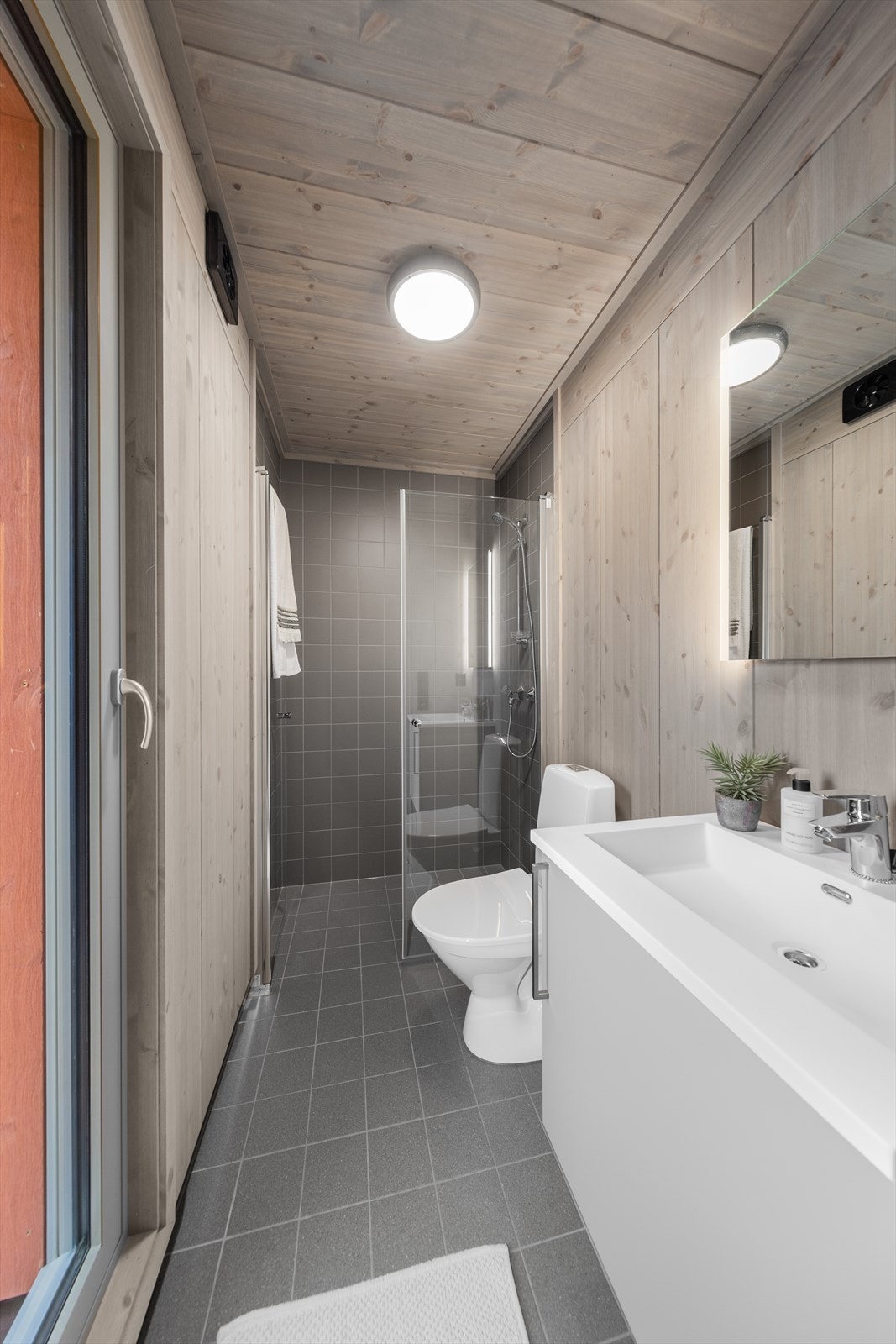 Badet inneholder wc, dusjhjørne og servant med underskap. Galleribilde