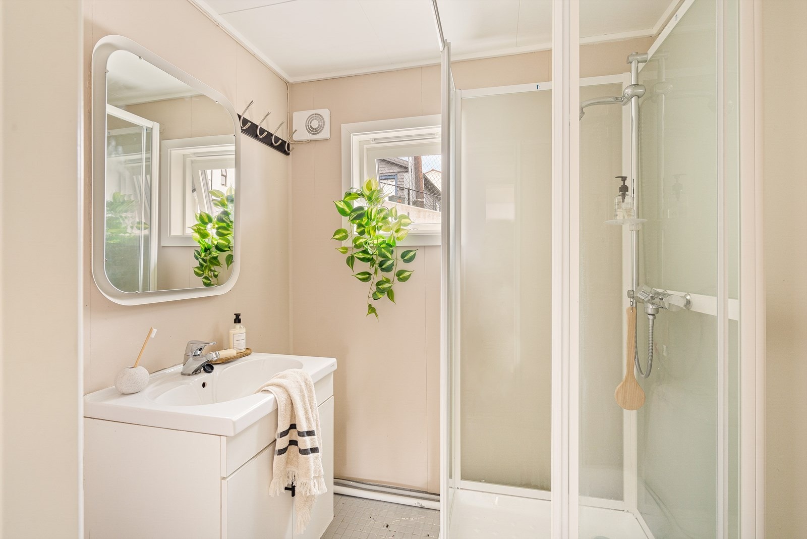 Badet inneholder dusjkabinett, servant og speil. Veggene har baderomsplater og taket har himlingsplater. Galleribilde