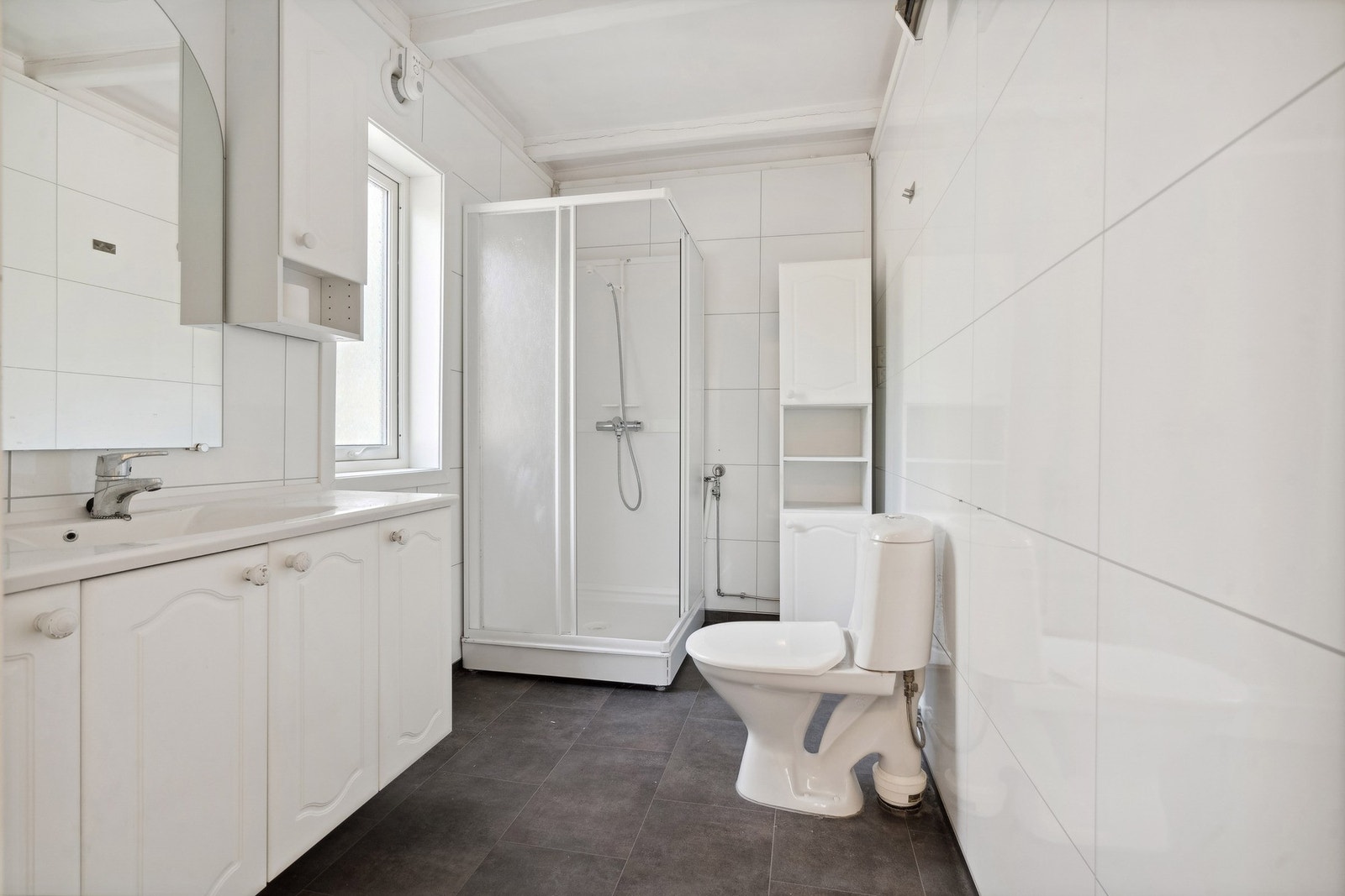 Badet har fliser på gulv og baderomsplater på vegg - her finner du toalett baderomsinnreding og dusjkabinett Galleribilde