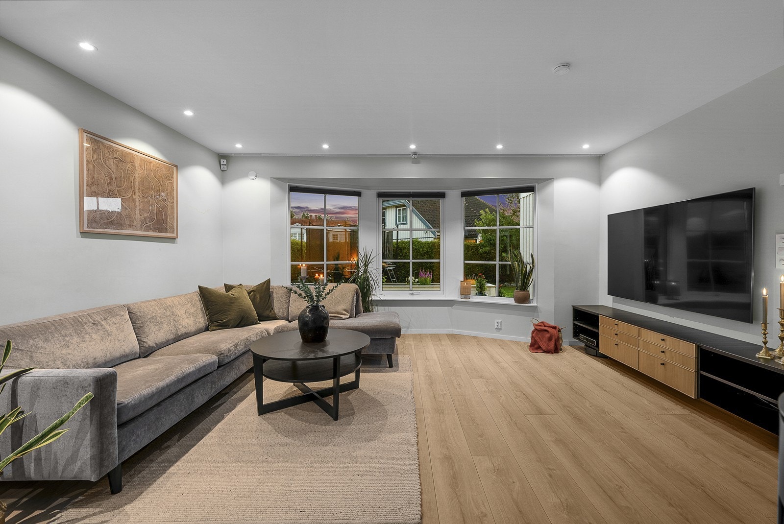 Stuen er pen og romslig, med en stor vindusflate som slipper inn rikelig med dagslys, samtidig som den bringer noe av det grønne inn i rommet. Galleribilde