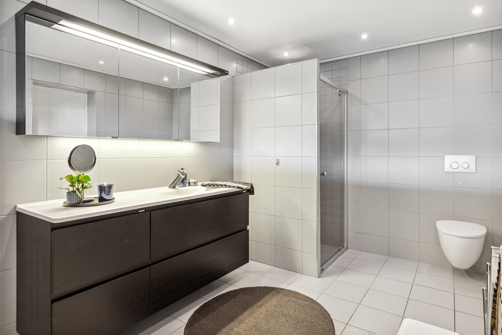 Badet holder en tidsriktig standard med fine fargevalg, praktisk dusjhjørne, vegghengt toalett og badekar. Takstmann har vurdert rommet til TG1. Galleribilde